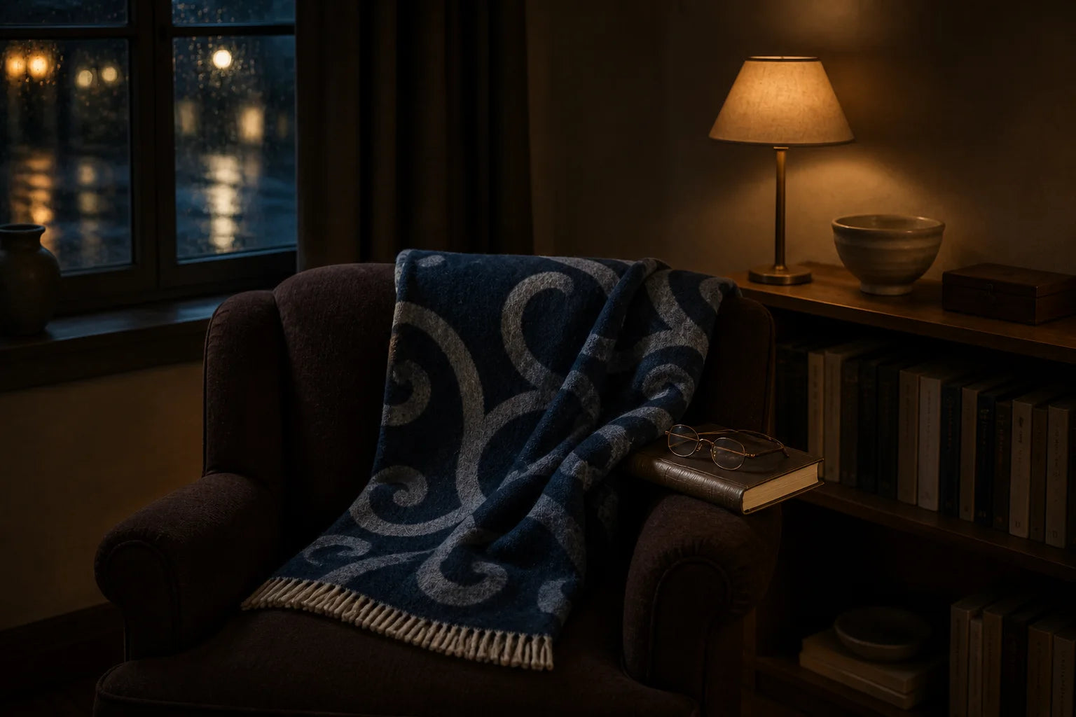 A navy patterned Sofia Toscano throw in a lamplit library on a rainy winter evening