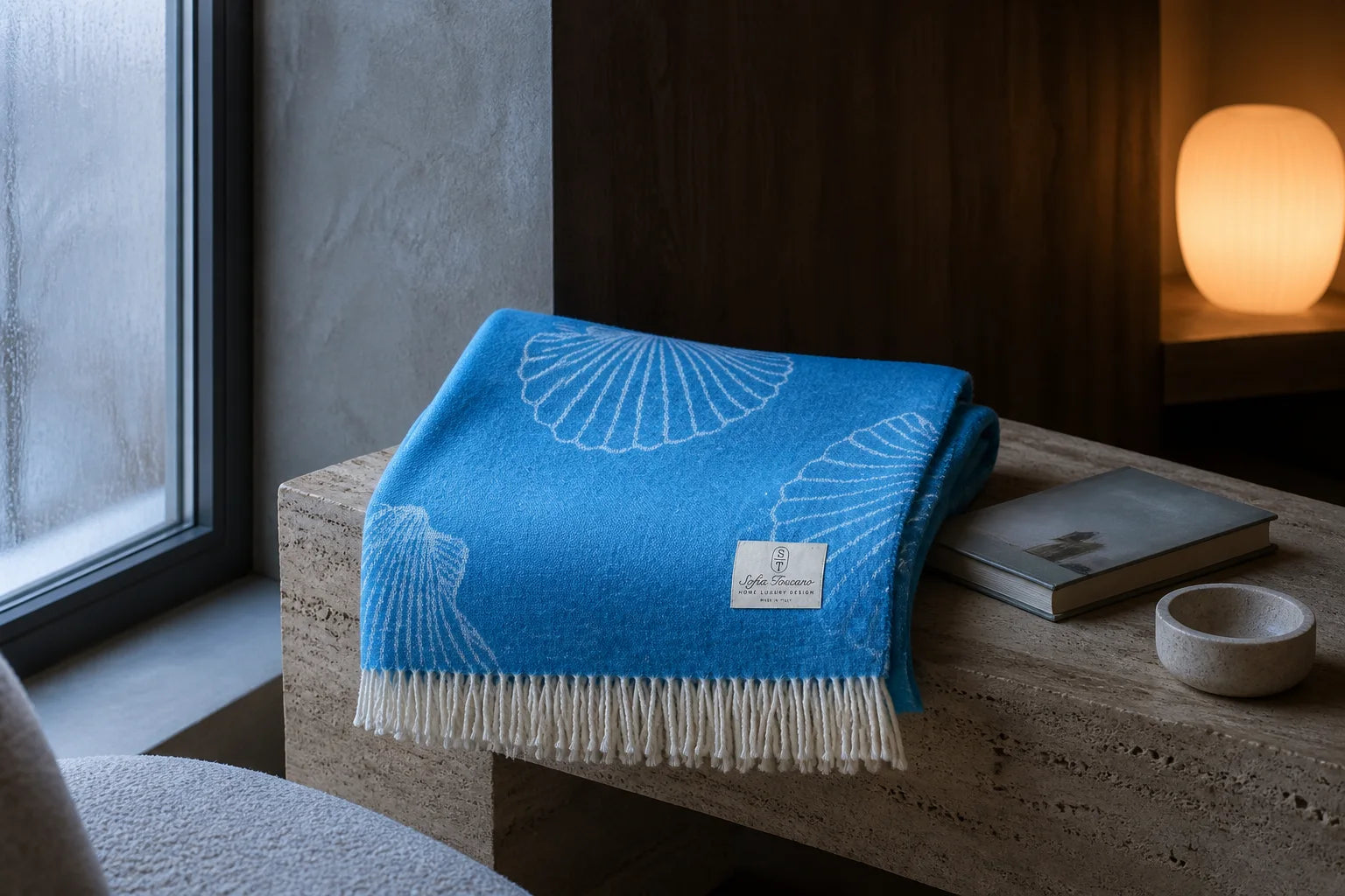Bright blue shell-patterned Sofia Toscano throw beside a winter window
